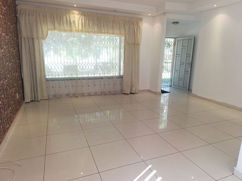 Spacious, light-filled living area featuring polished porcelain floor tiles, a textured feature wall, and direct access to the entrance.