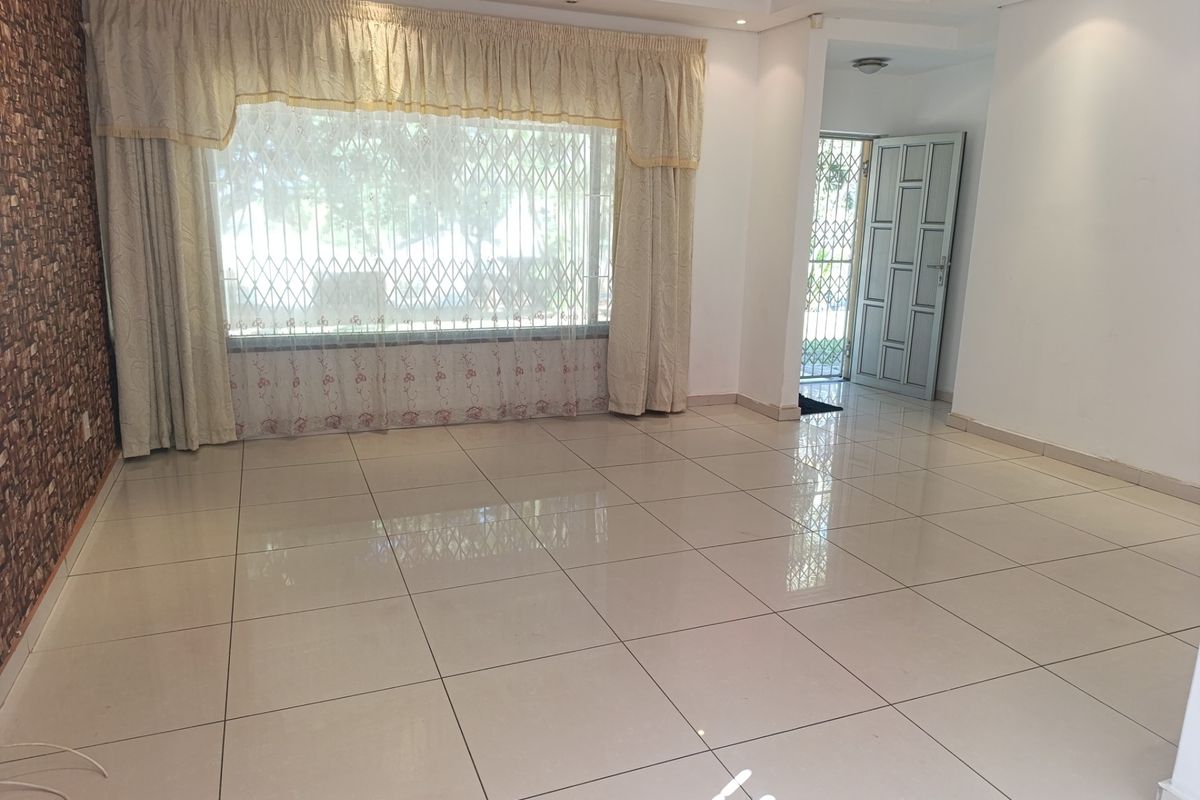Spacious, light-filled living area featuring polished porcelain floor tiles, a textured feature wall, and direct access to the entrance.