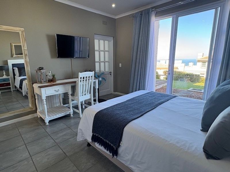 A well-lit bedroom featuring tiled flooring, recessed lighting, and a large sliding glass door providing access to an outdoor area with a view.