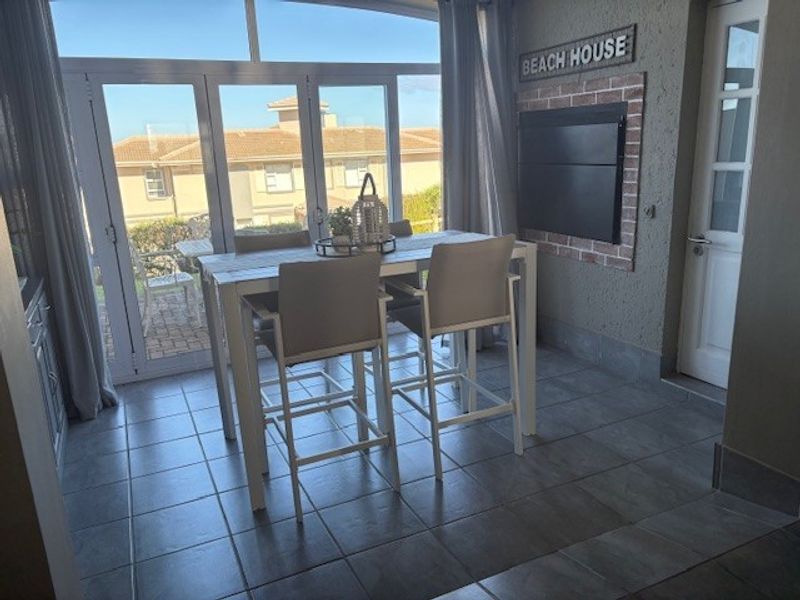 Enclosed patio area featuring tiled flooring, a built-in braai with brick surround, and large aluminium sliding doors providing access to the exterior.