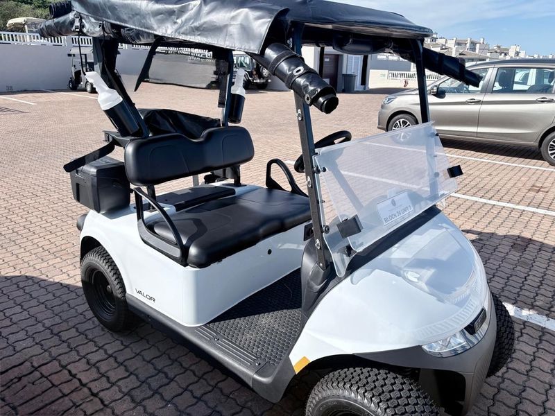 A golf cart parked in a paved parking area within a residential complex.