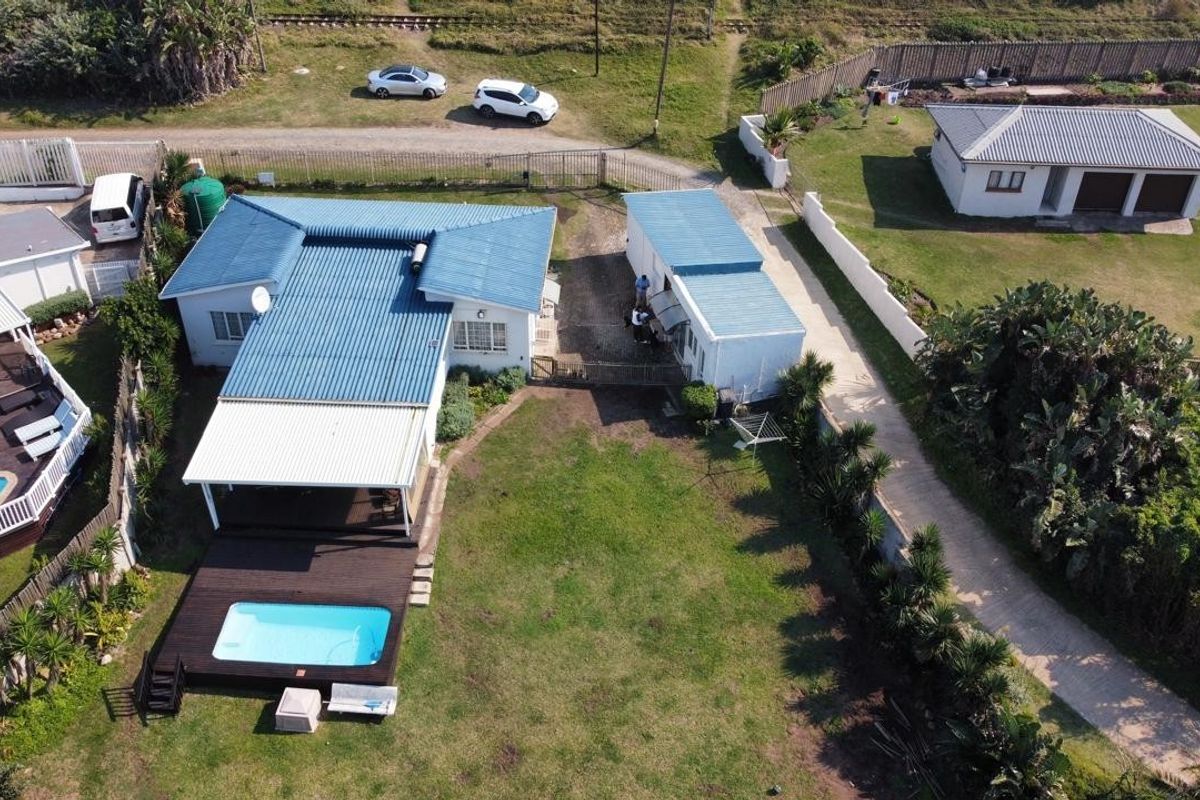 Aerial view of the property featuring a main house with a metal roof, a swimming pool with a timber deck, and a separate outbuilding.