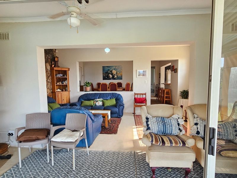 Open-plan living area featuring a stone accent wall, ceiling fan, and large sliding glass doors providing seamless access to the outdoor space.