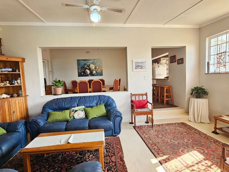 Spacious open-plan living area featuring a stone accent wall, ceiling fan, and a raised transition area leading to the dining and kitchen spaces.