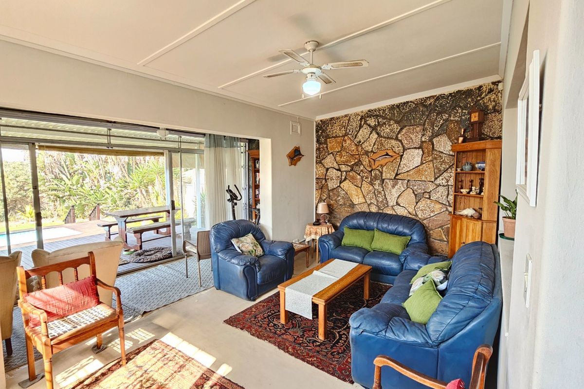 Spacious living room featuring a distinctive stone accent wall, ceiling fan, and large sliding glass doors providing seamless access to the outdoor patio area.