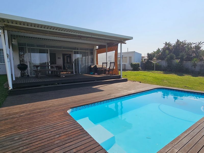 Outdoor entertainment area featuring a swimming pool, timber decking, and a covered patio with sliding door access to the main house.