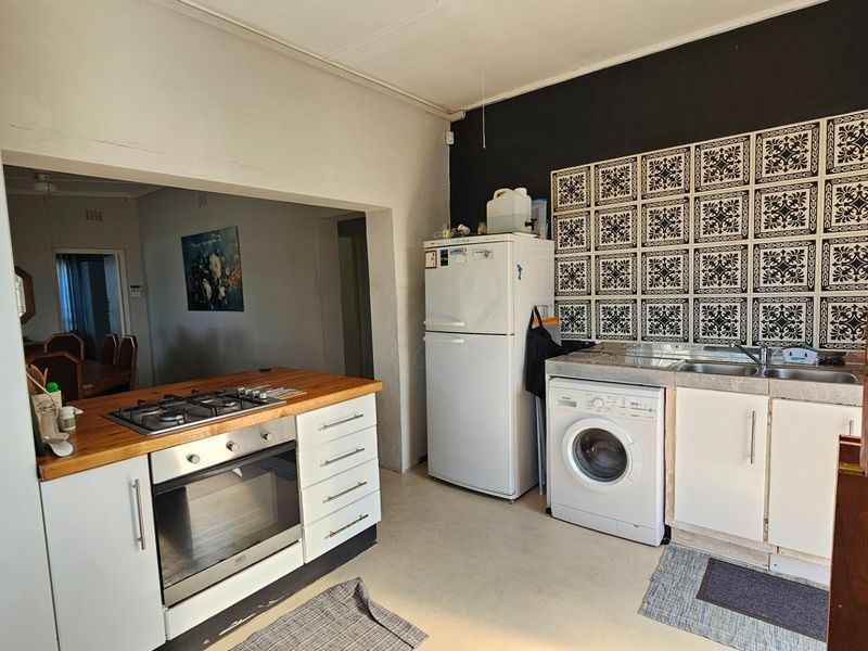 Functional kitchen featuring a gas hob, wooden countertop, decorative tiled splashback, and integrated cabinetry with adjacent laundry area.