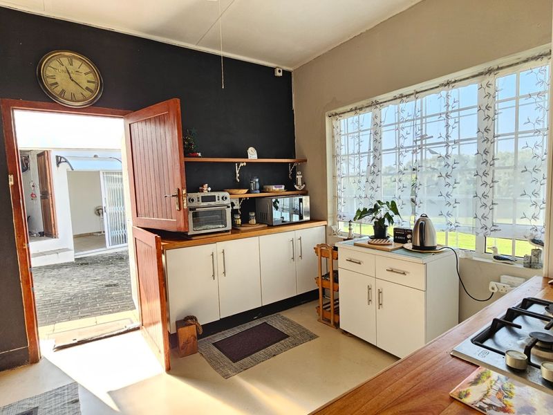 Kitchen featuring white cabinetry, wooden countertops, and a gas hob, with direct access to an outdoor area through a stable-style door.
