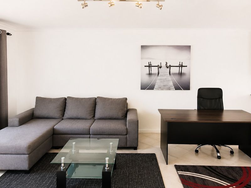 Open plan living area featuring tiled flooring, modern kitchen cabinetry with an extractor fan, and large windows allowing for natural light.