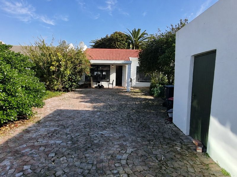 Front exterior view of the property featuring a cobblestone driveway, tiled roof, and secure entrance with security bars.