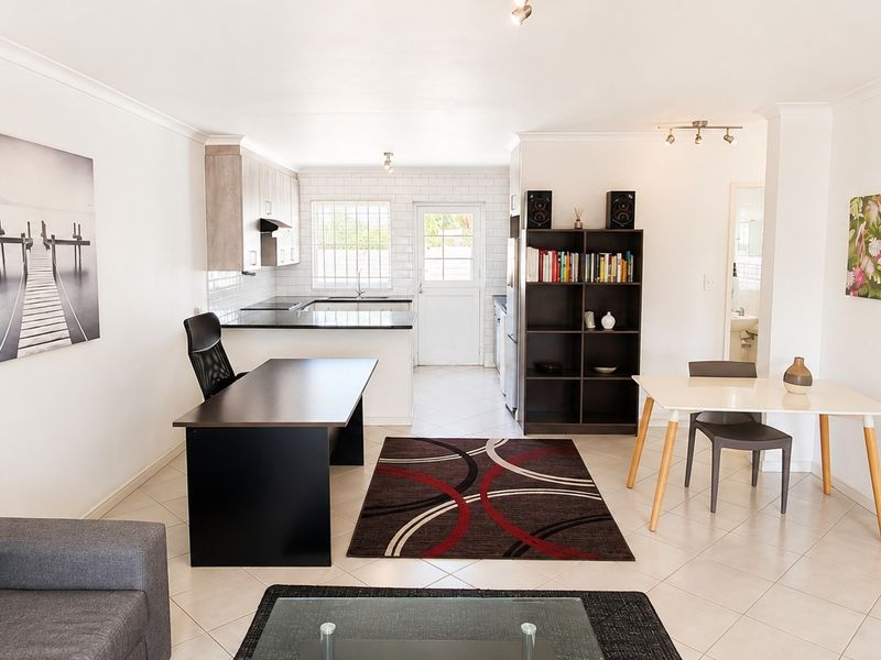 An open-plan living and kitchen area featuring tiled flooring, modern cabinetry, and a functional layout suitable for versatile living and dining arrangements.