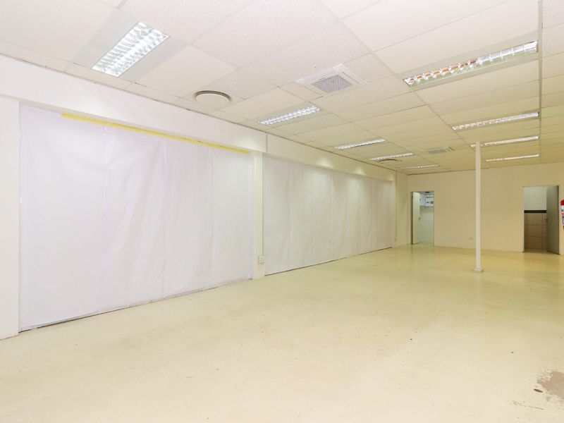 A vacant open-plan retail space featuring a suspended ceiling, recessed lighting, and a neutral finish, suitable for various commercial business applications.