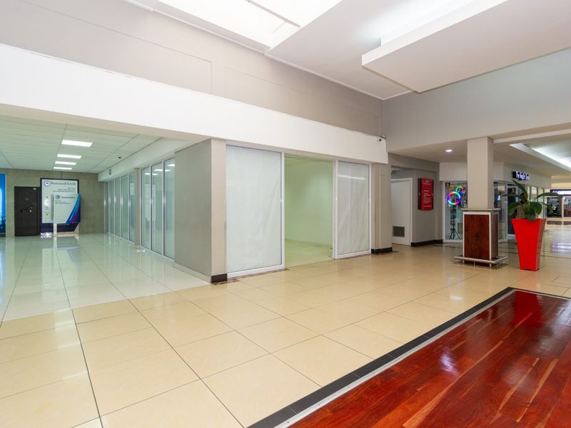 Spacious retail unit within a shopping center, featuring tiled flooring, modern drop ceilings, and glass storefront partitions suitable for various commercial uses.