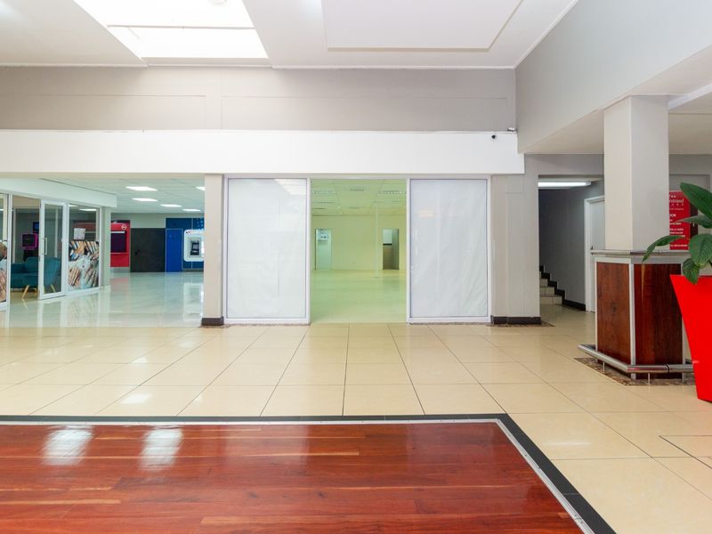 Spacious open-plan retail unit featuring a combination of tiled and hardwood flooring, recessed lighting, and large glass entry doors.