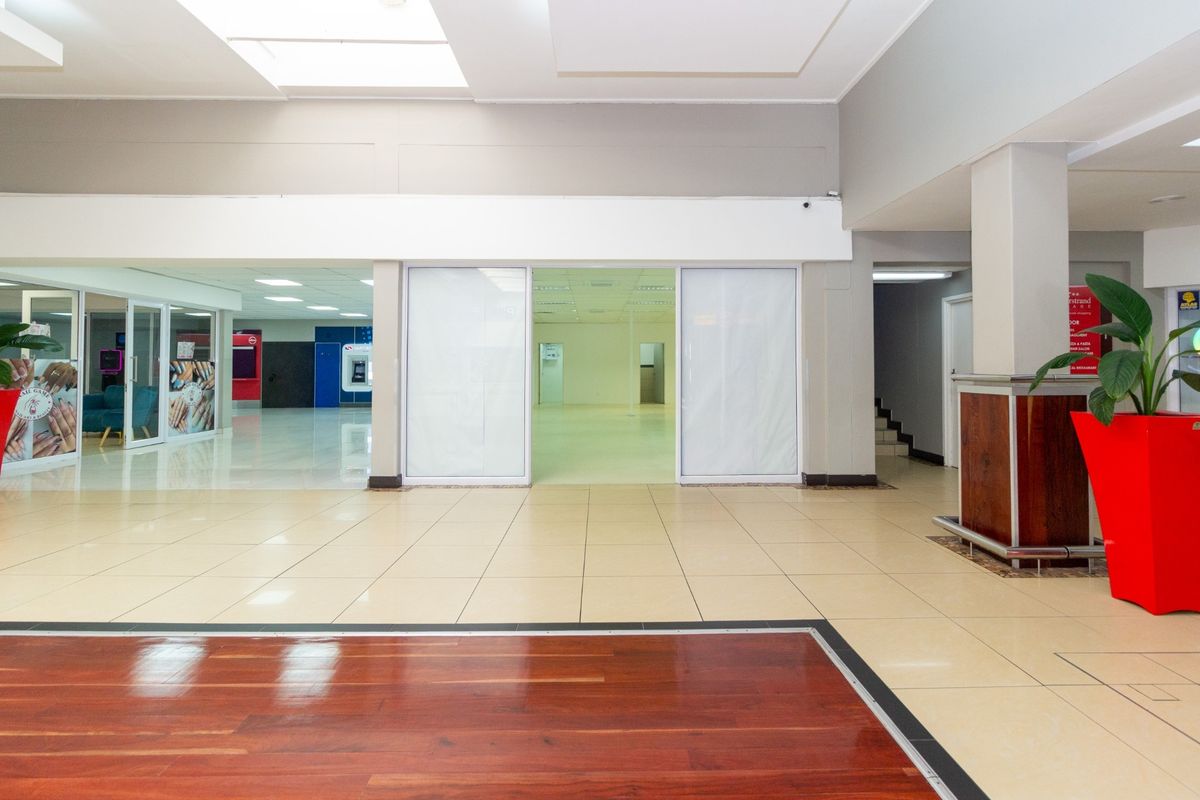 Spacious open-plan retail unit featuring a combination of tiled and hardwood flooring, recessed lighting, and large glass entry doors.