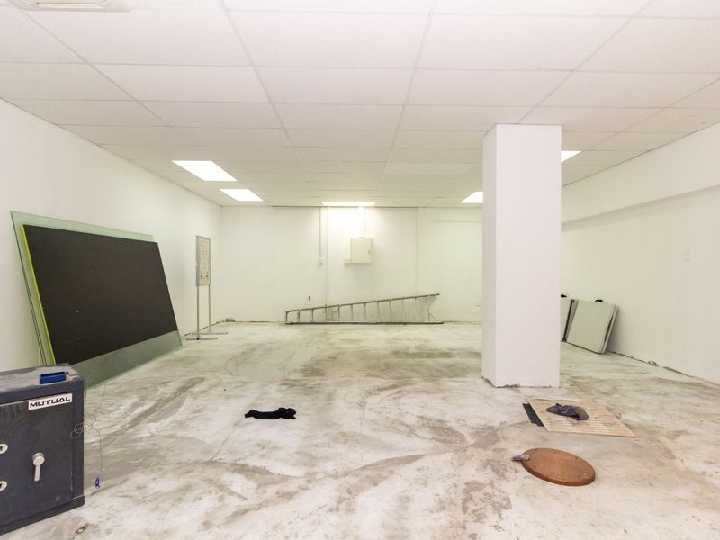An open-plan retail space featuring a suspended ceiling, recessed lighting, and an exposed concrete floor, offering a blank canvas for custom fit-out.