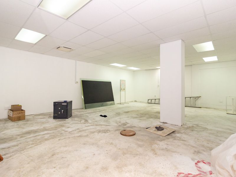 An open-plan retail space featuring a suspended ceiling with recessed lighting and an unfinished concrete floor, suitable for various commercial fit-out options.