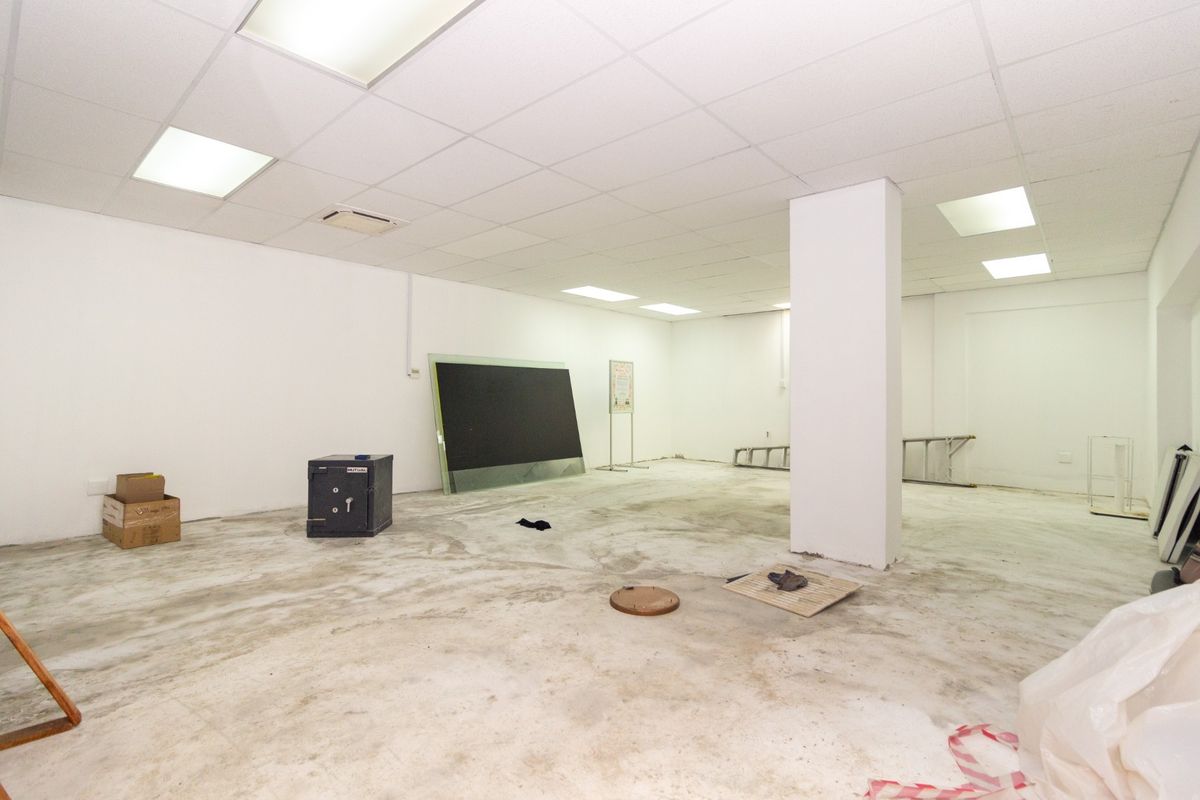 An open-plan retail space featuring a suspended ceiling with recessed lighting and an unfinished concrete floor, suitable for various commercial fit-out options.