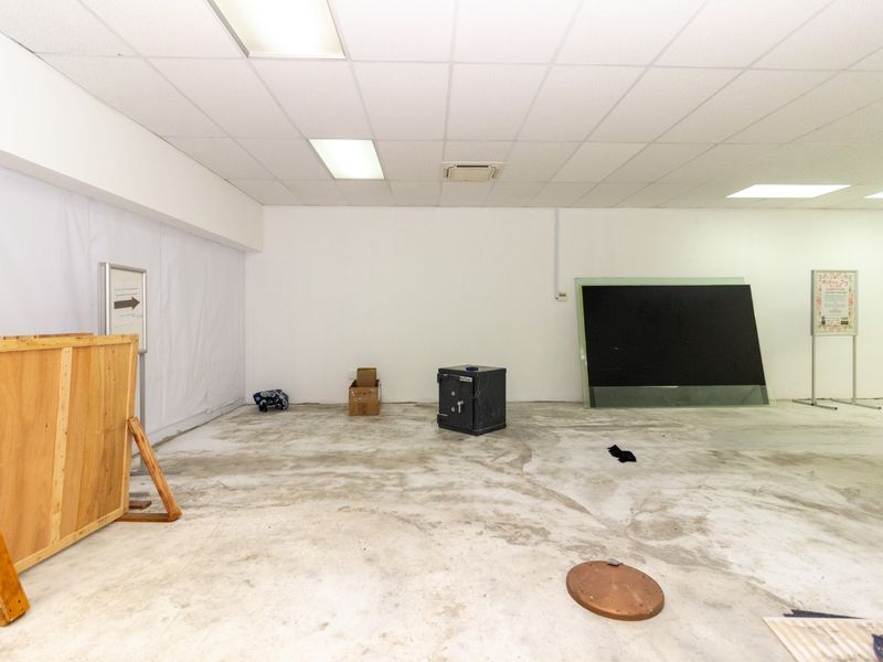 An open-plan utility or retail space featuring a suspended ceiling with recessed lighting and unfinished concrete flooring, suitable for various commercial fit-out options.