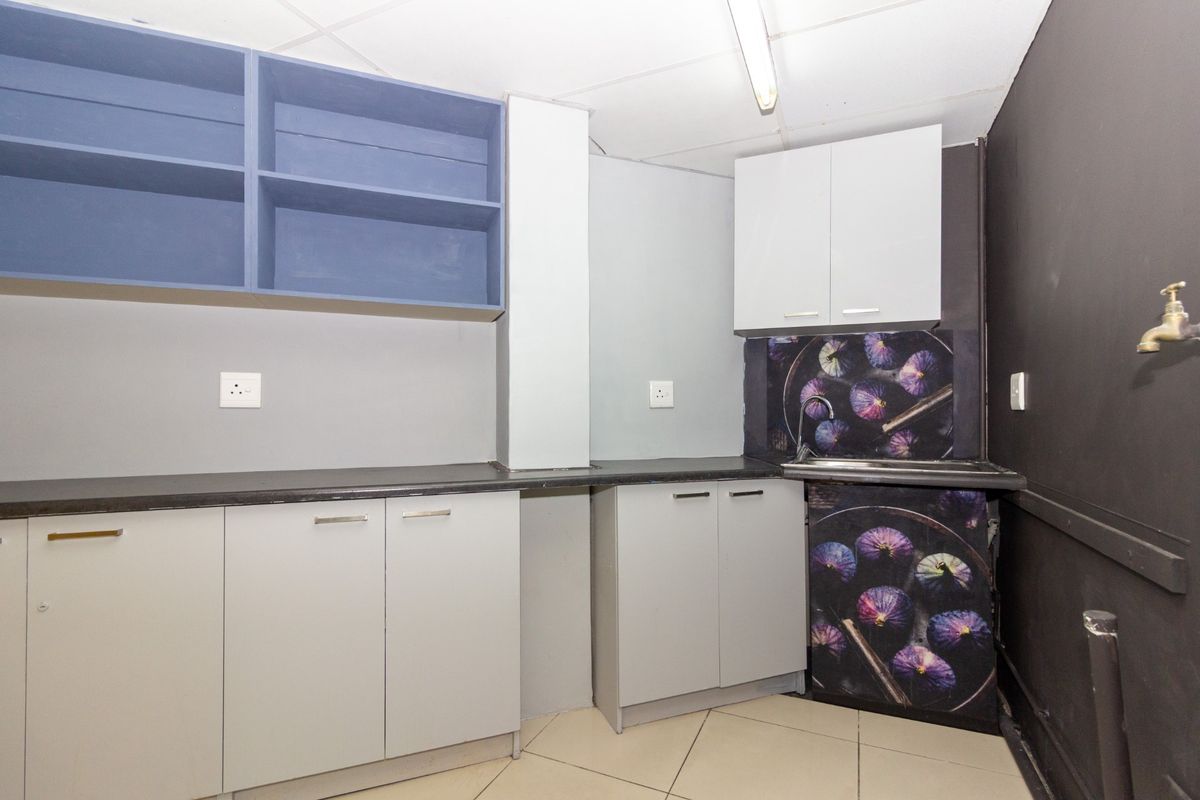 A functional kitchen area featuring built-in cabinetry, laminate countertops, and a stainless steel sink, currently vacant and ready for updates.