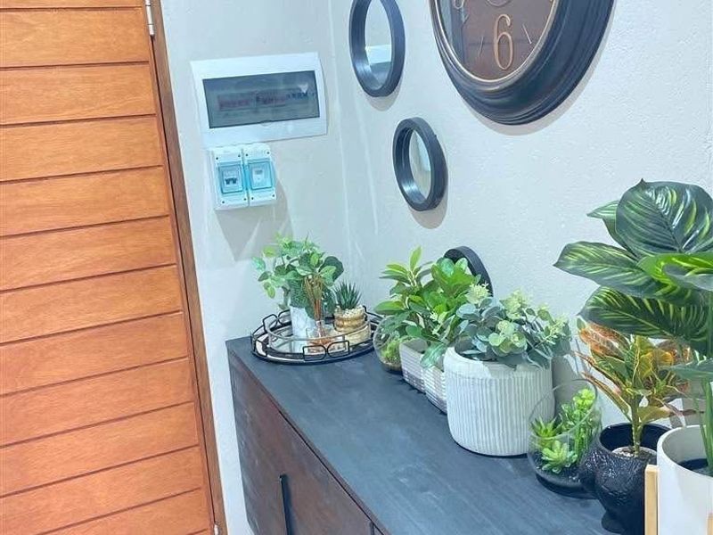 A welcoming entryway featuring a modern timber front door and a wall-mounted electrical distribution board.