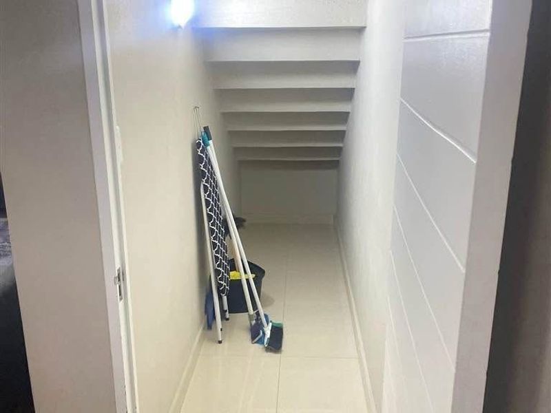 A clean under-stair utility storage space featuring tiled flooring and a built-in structure, providing convenient additional storage capacity within the townhouse.