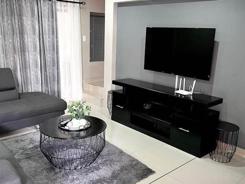 A modern living room featuring large format floor tiles, a recessed wall section for media, and neutral wall tones.