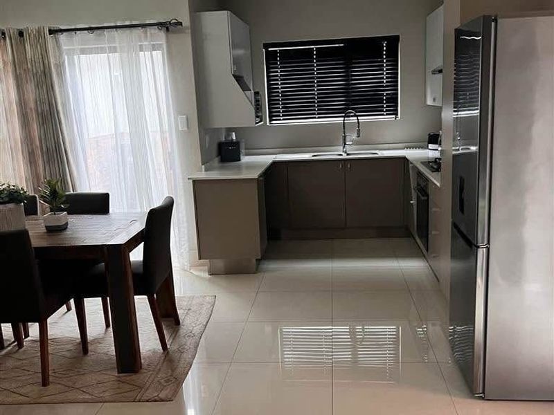 Open plan kitchen and dining area featuring modern cabinetry, tiled flooring, and direct access to the patio through sliding glass doors.
