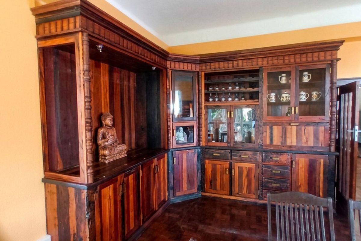 A living area featuring extensive custom-built wooden cabinetry with integrated glass display shelving and traditional parquet flooring.