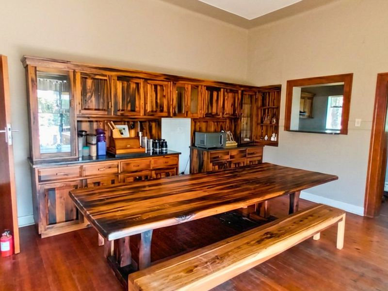 Dining room featuring extensive built-in wooden cabinetry, hardwood flooring, and a convenient pass-through window connecting to the adjacent space.