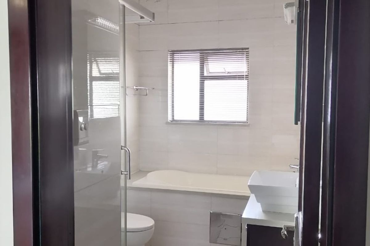A functional bathroom featuring a built-in bathtub, glass shower enclosure, and a modern vessel sink vanity with tiled finishes.