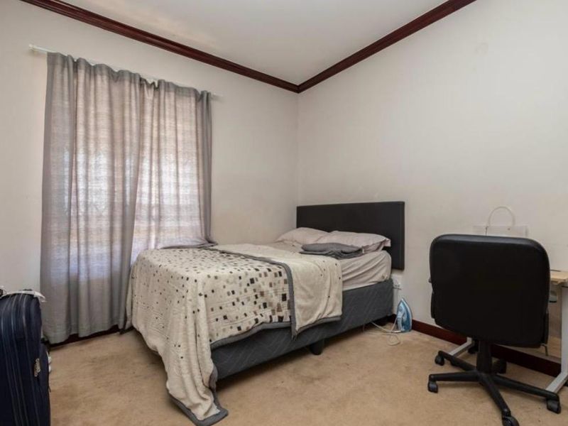 A bedroom featuring carpeted flooring, timber crown molding, and timber skirting boards. The room requires cosmetic updates to the wall finishes and flooring.