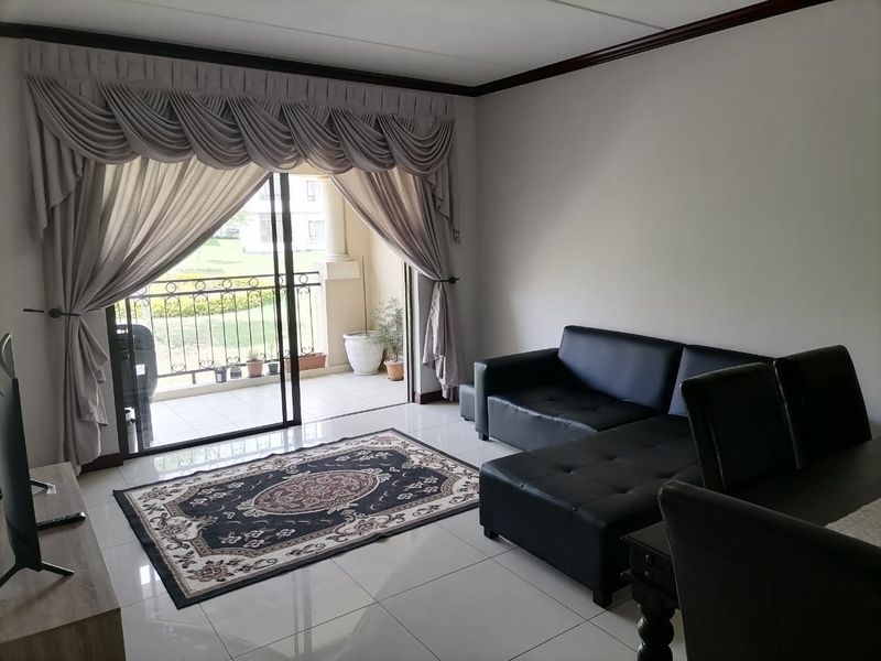 Open plan living area featuring tiled flooring, crown molding, and large sliding glass doors providing direct access to a private balcony.