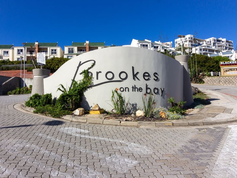 The entrance to Brookes on the Bay, featuring a prominent property sign, paved driveway, and landscaped garden area.