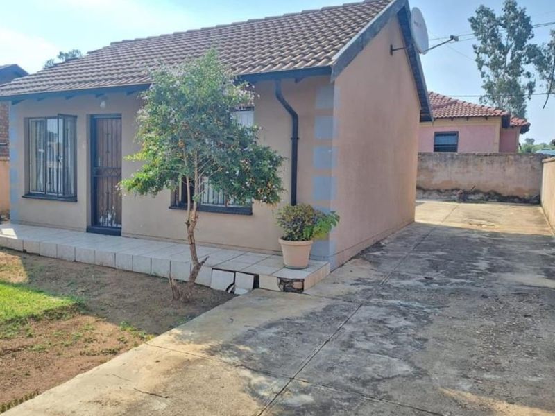 Front view of a single-story house featuring a tiled roof, security bars on windows, a security gate, and a concrete driveway.
