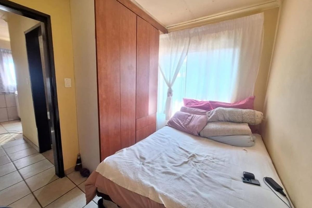 A compact bedroom featuring a built-in wooden wardrobe and tiled flooring, requiring cosmetic updates to improve its overall condition and appeal.