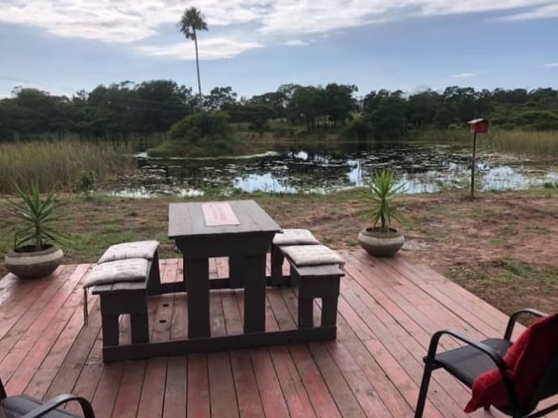 An outdoor timber deck area overlooking a natural pond and surrounding landscape.