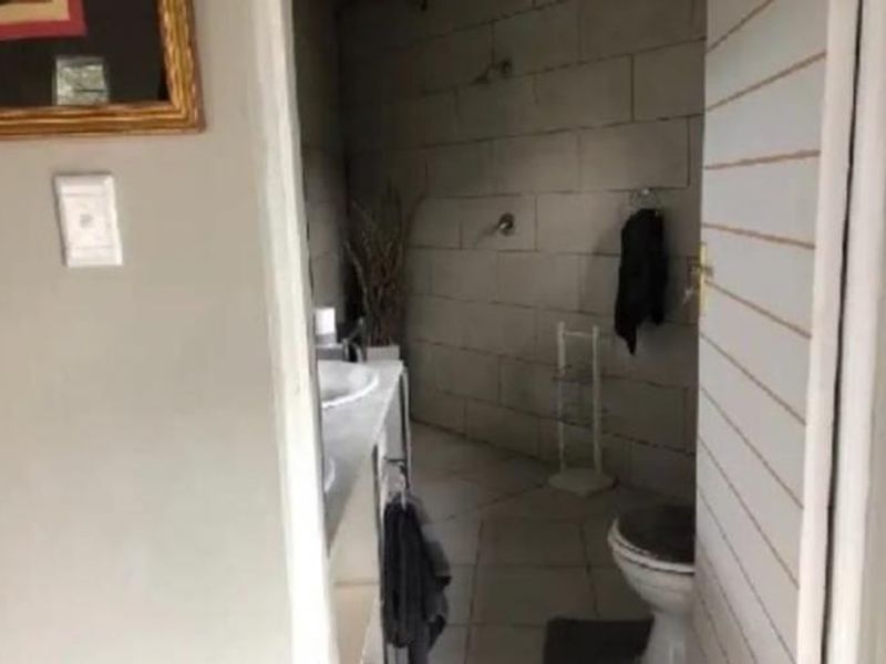 A functional bathroom featuring tiled walls and flooring, a vanity basin, and a shower area.
