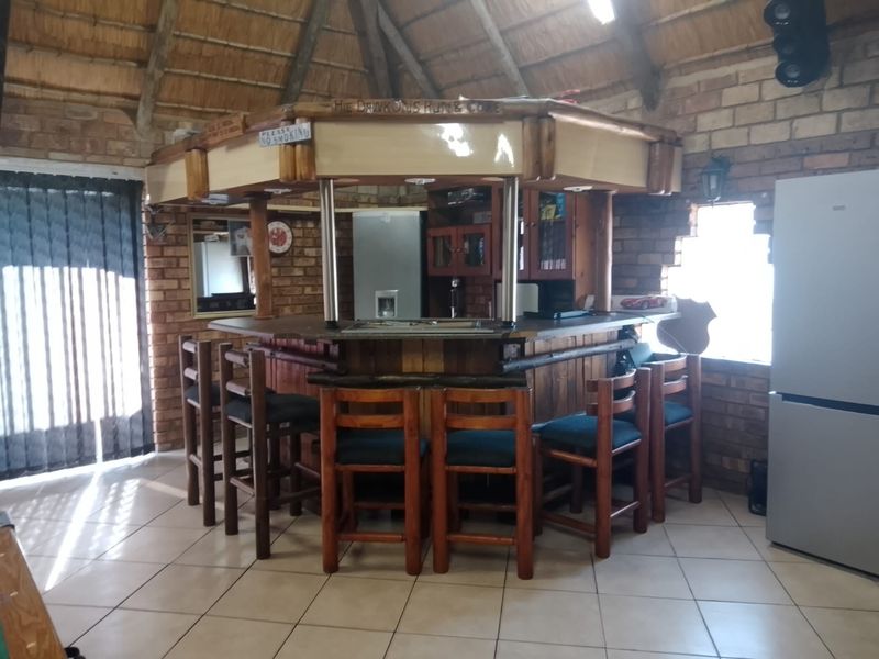 A rustic bar area featuring a built-in counter, exposed brick walls, and a traditional thatched roof, providing a unique entertainment space.