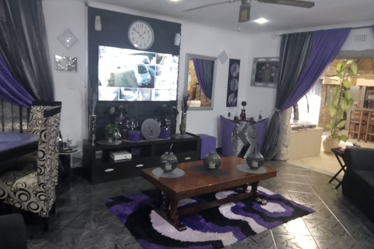 A living room featuring tiled flooring, recessed lighting, and a ceiling fan, with an open layout connecting to adjacent living spaces.