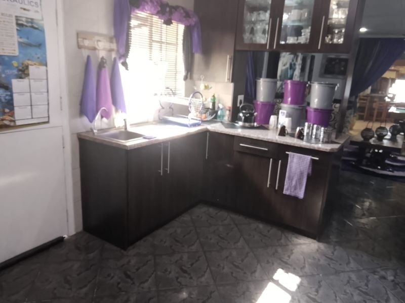 A compact kitchen area featuring dark wood-finish cabinetry, laminate countertops, and tiled flooring, providing a functional prep space.