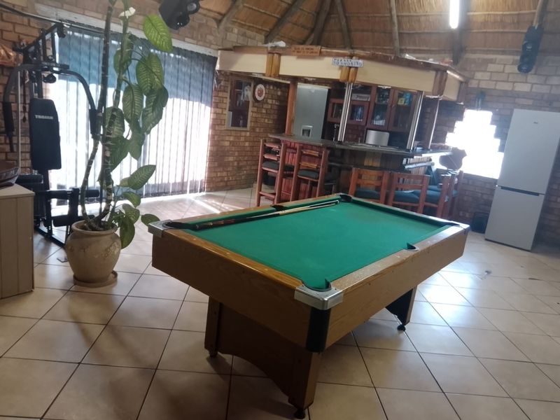 A rustic entertainment area featuring a built-in bar, exposed brick walls, and a traditional thatched roof, providing a casual space for social gatherings.