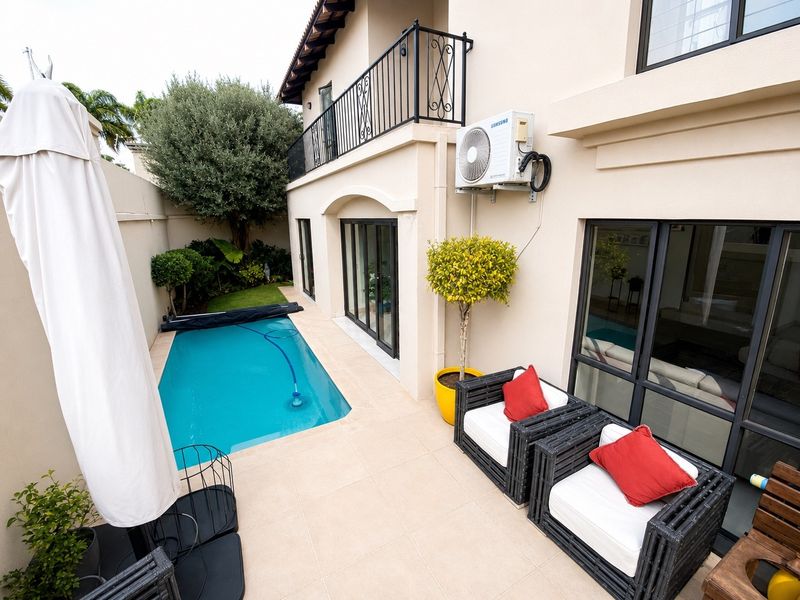 A well-maintained rear courtyard featuring a compact swimming pool, tiled patio area, and access to the home via sliding glass doors.