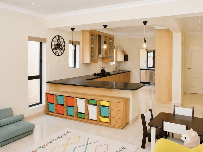 Open-plan kitchen featuring light wood cabinetry, dark countertops, and a functional scullery, seamlessly flowing into the living and dining area.