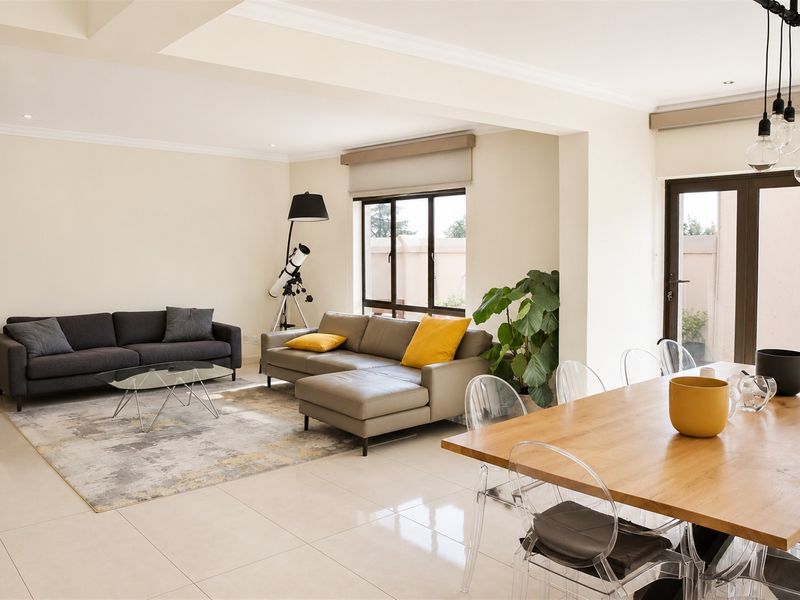 Spacious open-plan living and dining area featuring neutral tiled flooring, recessed ceiling details, and large glass doors providing access to the exterior.