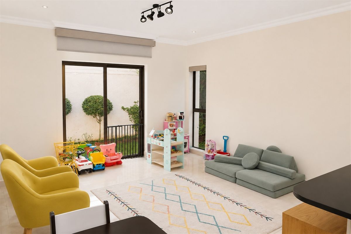 A bright and spacious living area featuring tiled flooring, modern track lighting, and large sliding glass doors providing access to the outdoor space.