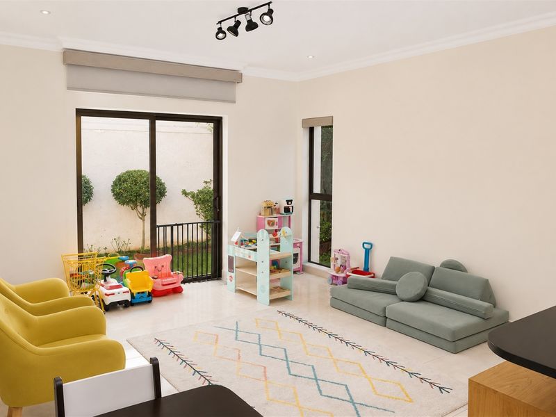 A bright and spacious living area featuring tiled flooring, modern track lighting, and large sliding glass doors providing access to the outdoor space.