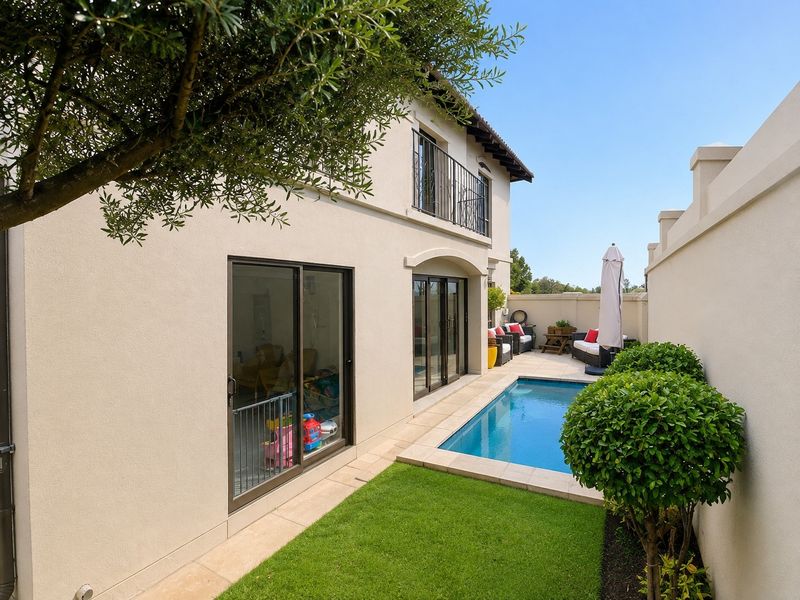 Rear exterior view featuring a swimming pool, paved surround, manicured lawn, and sliding glass doors leading into the home.