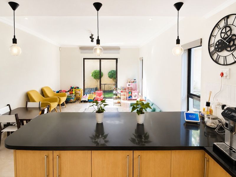 Open-plan living and kitchen area featuring a central island with stone countertops, modern pendant lighting, and sliding doors leading to the outdoor space.