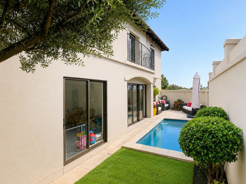 Rear exterior view featuring a swimming pool, manicured lawn, and sliding glass doors leading into the home, complemented by an upper-level balcony.